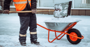 Worker removes accumulated snow into a wheelbarrow